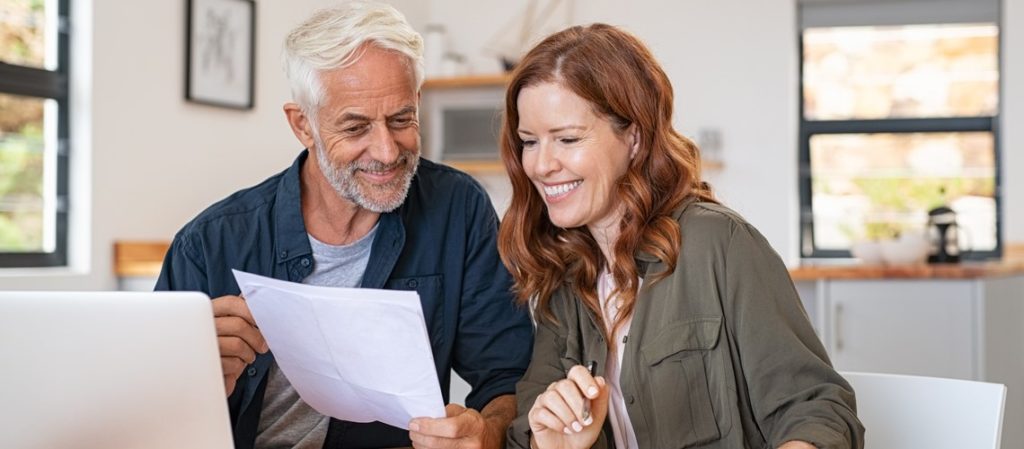 couple smiling while looking at a paper