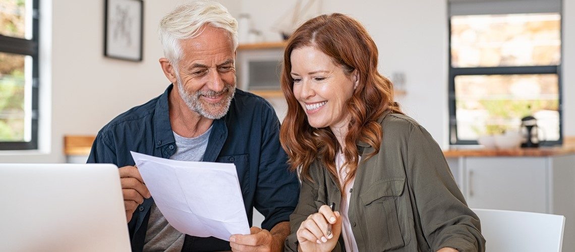 man and woman smiling while looking at a paper