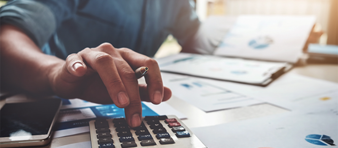 man looking at papers while using a calculator