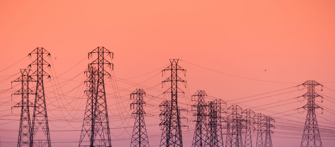 Sunset view of high voltage electricity towers on the shoreline of San Francisco bay area; California